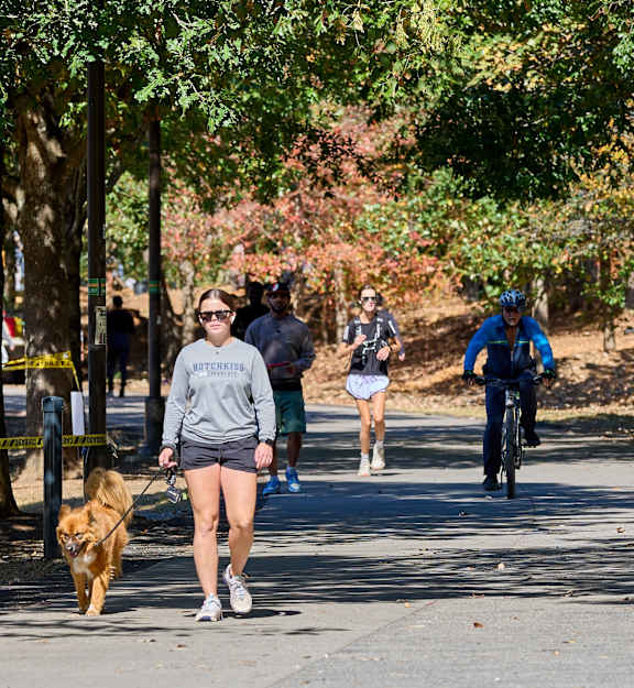 A group of people walking in a park with a dog.