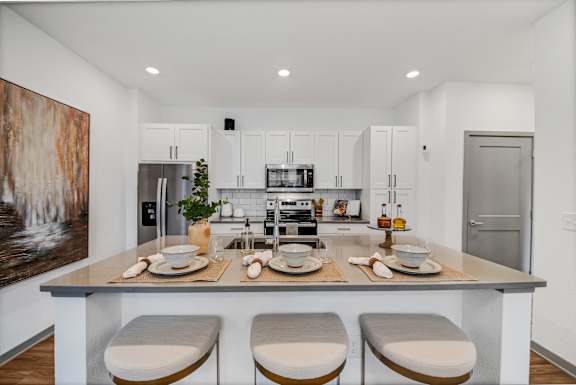 a kitchen with white cabinets and a island with four chairsat The BLVD at Wilson Crossings, Wyoming, MI