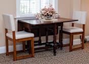 Thumbnail 13 of 17 - A dining room with a table and chairs.