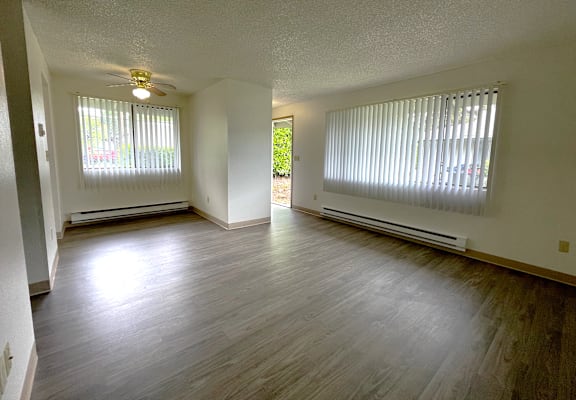 A room with a ceiling fan and two windows with blinds.