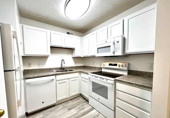 A kitchen with white appliances and cabinets.