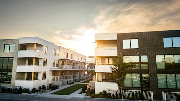 A modern apartment complex with a sunset in the background.