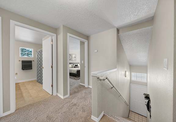 A bedroom with a carpeted floor and a staircase leading to the second floor.