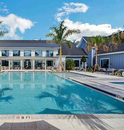 a large pool in front of a building with palm trees at The Sophia, Venice, FL, 34275