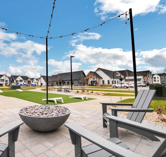 a park with benches and fire pits with houses in the background at The BLVD at Wilson Crossings, Michigan, 49418