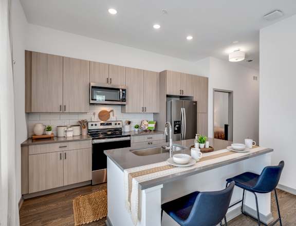 a kitchen with a large island with two blue chairs at The Boardwalk at Tradition in Port St Lucie, FL 34987
