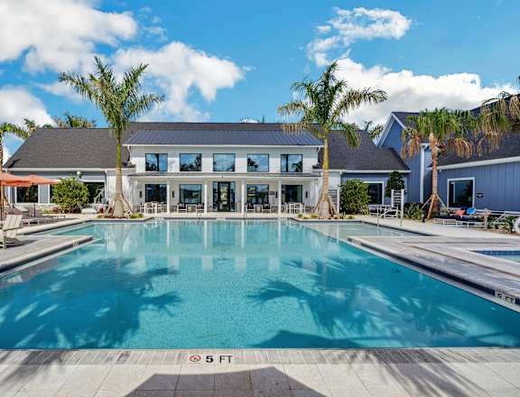 a large pool in front of a building with palm trees at The Sophia, Venice, FL, 34275