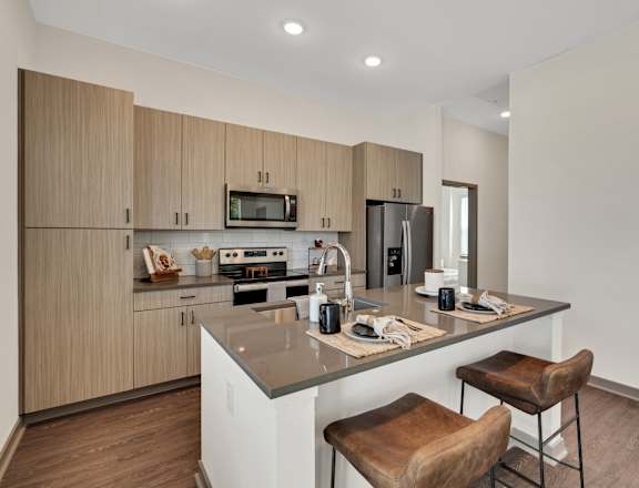 a kitchen with a large island with two bar stools at The Sophia, Venice, FL, 34275