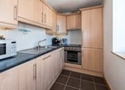 Thumbnail 1 of 3 - a kitchen with wooden cabinets and a microwave and a sink
