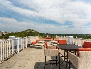 A patio with orange chairs and a table overlooking a cityscape.