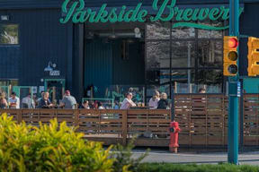a group of people sitting on benches in front of a brewery