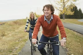 a man and a woman riding bikes down a road