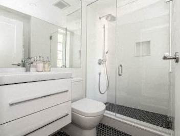 A white bathroom with a toilet, sink, and shower.