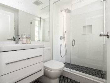 A white bathroom with a toilet, sink, and shower.