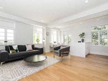 A modern living room with a grey sofa and a wooden floor.