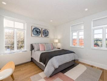 A bedroom with a large bed and two clocks on the wall.