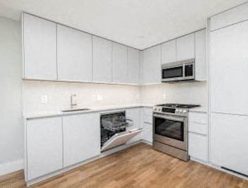 A kitchen with white cabinets and a stainless steel oven.