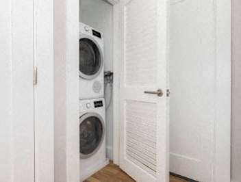 A white door is open to a laundry room with two washing machines.