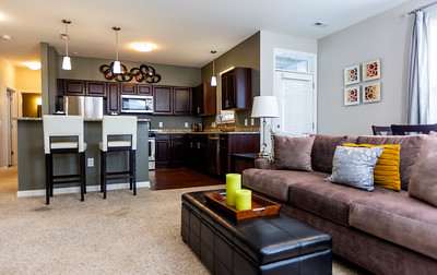 A brown couch with a yellow candle on a coffee table in a living room.
