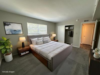 A bedroom with a bed, nightstands, and a plant.