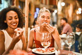 two women eating pizza at a restaurant