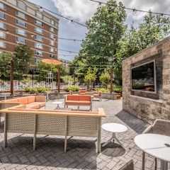 A patio with a table and chairs is surrounded by a brick wall and a building.