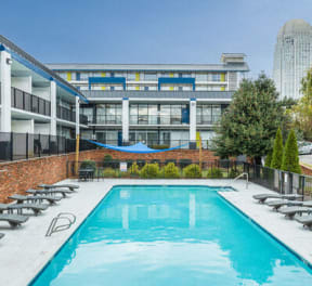 a swimming pool with chairs and a building in the background