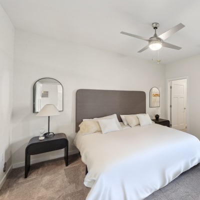 a bedroom with a large white bed and a ceiling fan