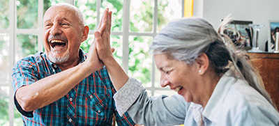a man and a woman giving each other a high five while sitting at a table with cards