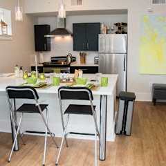 A kitchen with a white table and black chairs.