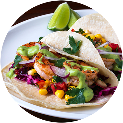 a plate of tacos with shrimp and vegetables and a lime