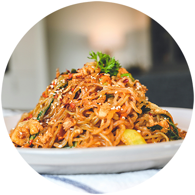 A plate of noodles with shrimp and garnished with parsley.