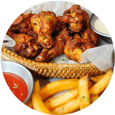 A basket of chicken wings and fries with dipping sauces.