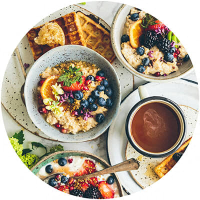 A breakfast spread with oatmeal, berries, and waffles.