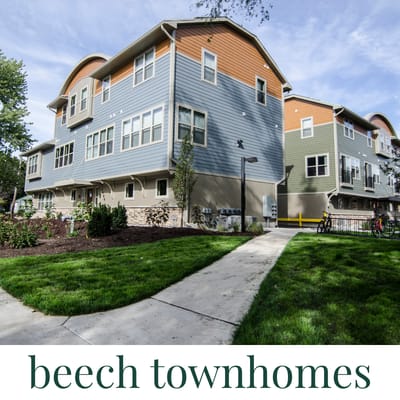 A beech townhomes building with a sidewalk in front.