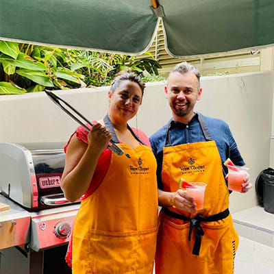 a man and a woman wearing orange aprons holding drinks