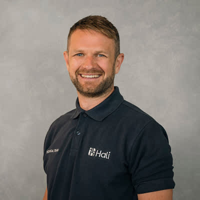 A man with a beard wearing a black polo shirt with the word "Hati" on it.