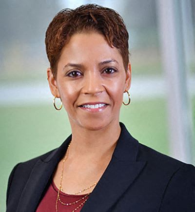 a woman wearing a black suit and a red shirt and a necklace