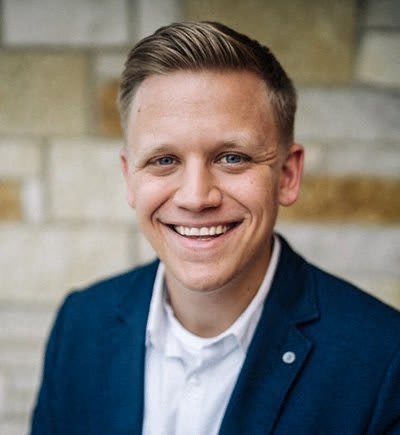 a smiling man wearing a blue jacket and a white shirt