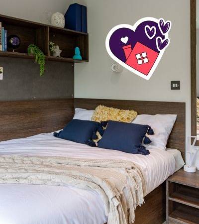 A bedroom with a bed, pillows, a blanket, and a shelf with decorative items.