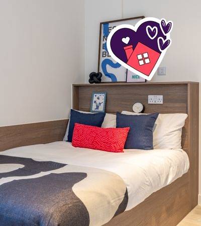 A bed with a white sheet and a red pillow is in front of a wall with a heart-shaped decoration.