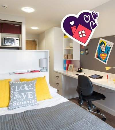 A bedroom with a bed, desk, and a pillow that says "Love".