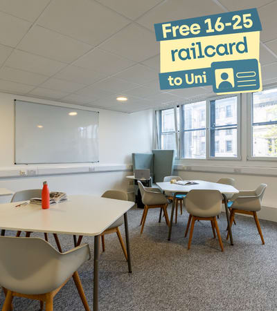 A white table with chairs and a sign offering a free railcard to university students.
