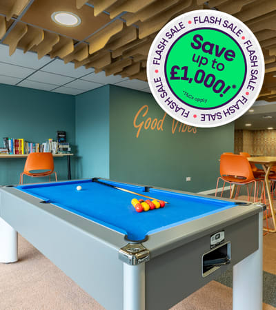 A pool table in a room with a sign that says "Save up to £1,000!"