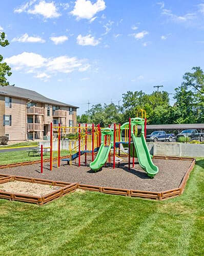 a playground with slides and other playground equipment in front of a building