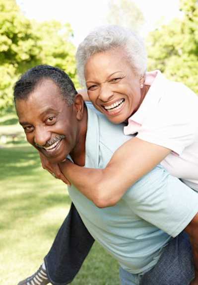 a man is giving a woman a piggyback ride in the park