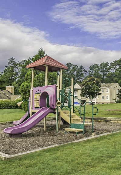 a playground with a purple slide in a park
