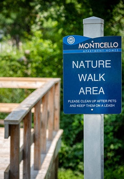 a sign for a nature walk area next to a wooden bridge