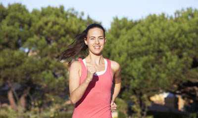 A woman in a pink tank top and black leggings runs down a road. at Arbours at Lafayette, Lafayette