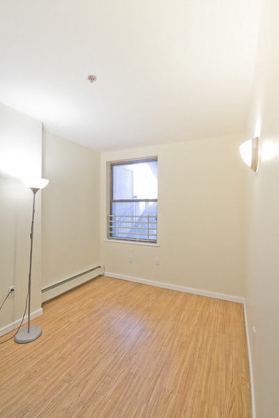 Bedroom with hardwood floors, window and wall lamp